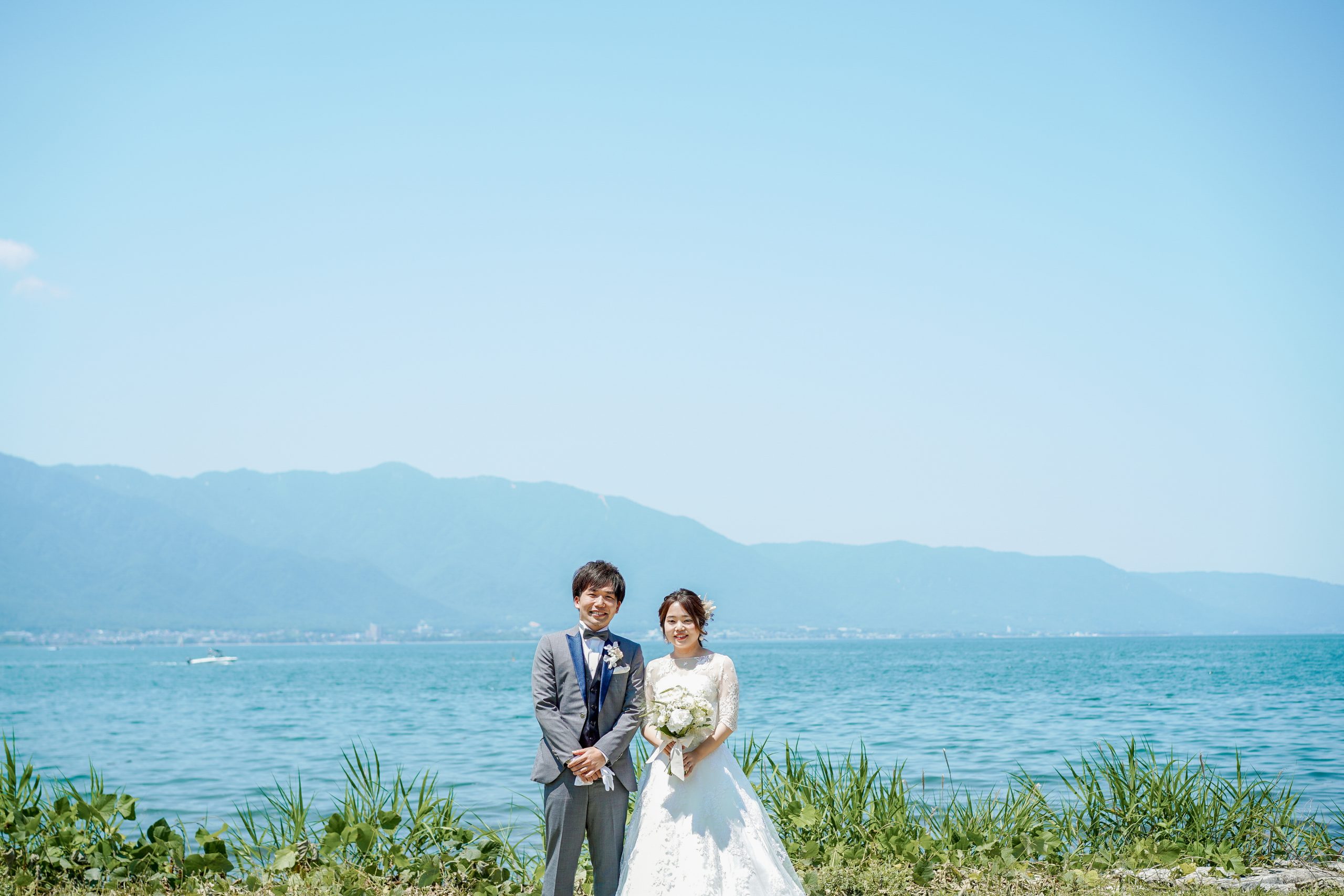 琵琶湖を背景に洋装で立つ新郎新婦｜滋賀フォトウェディング 前撮り