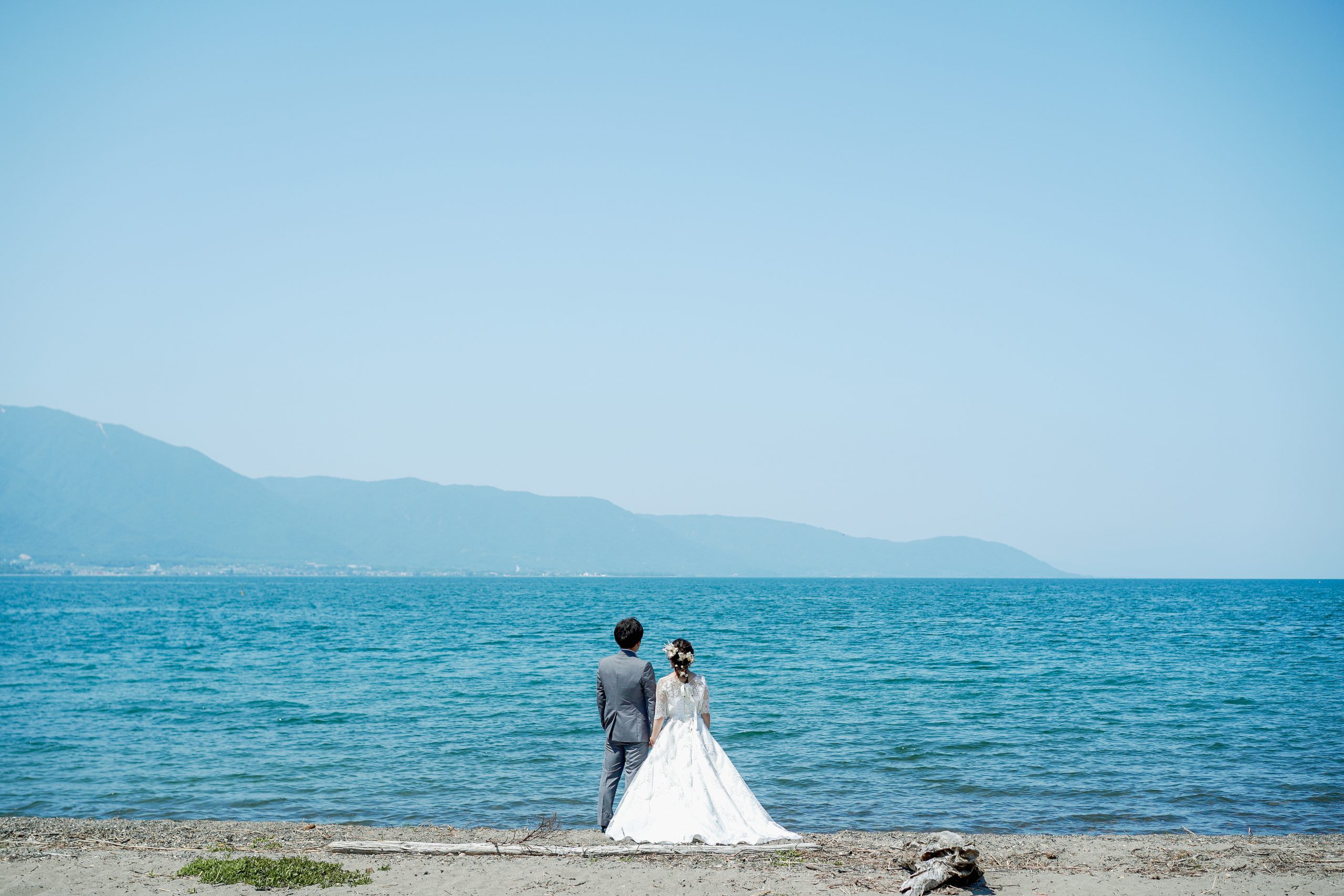 琵琶湖を背景に洋装で立つ新郎新婦｜滋賀フォトウェディング 前撮り